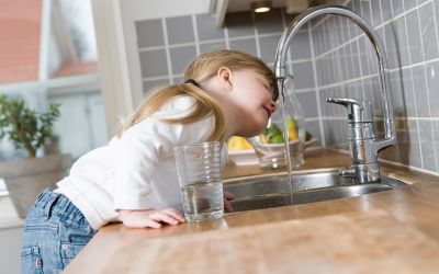 Bambina beve acqua dal rubinetto di casa